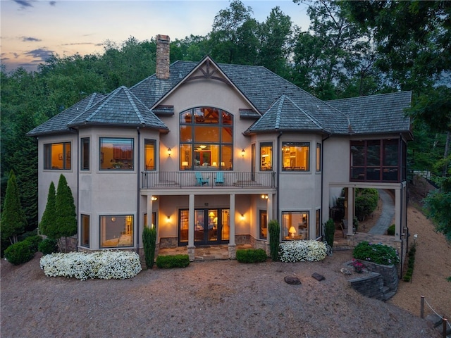 117 Misty Water Loop, Sunset, SC 29685 - back of property at dusk with a balcony, stucco siding, a chimney, french doors, and stone siding