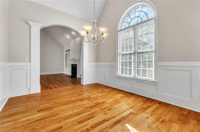 206 Waverly Hall Ln, Simpsonville, SC 29681 - unfurnished dining area with vaulted ceiling, a decorative wall, arched walkways, wainscoting, and light wood-style floors