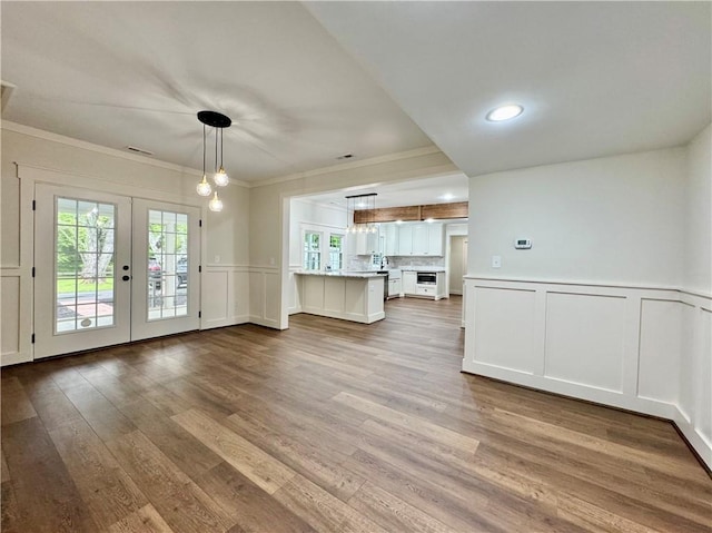 800 Holiday Dam Rd, Honea Path, SC 29654 - unfurnished living room featuring a decorative wall, french doors, crown molding, wood finished floors, and wainscoting
