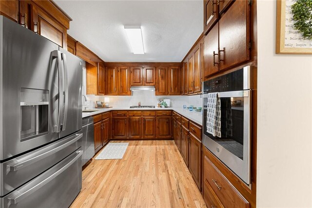 131 Shoreside Dr, Martin, GA 30557 - kitchen with appliances with stainless steel finishes, light wood-type flooring, light countertops, brown cabinets, and decorative backsplash