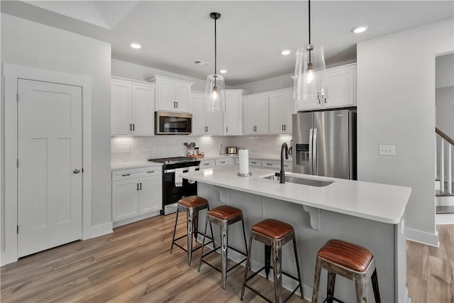 222 Grange Vally Ln, Central, SC 29630 - kitchen featuring stainless steel appliances, a sink, light wood-style flooring, a breakfast bar area, and white cabinets