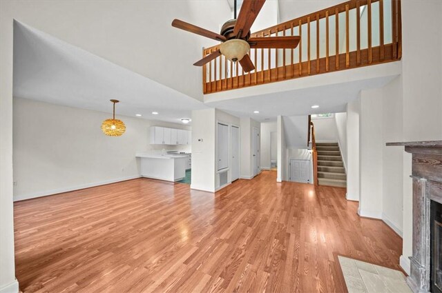 704 Loran Pointe Cir, Seneca, SC 29672 - unfurnished living room with stairs, a fireplace with flush hearth, light wood-style floors, baseboards, and a towering ceiling