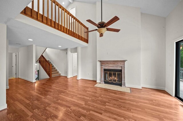 704 Loran Pointe Cir, Seneca, SC 29672 - unfurnished living room with stairs, wood finished floors, high vaulted ceiling, ceiling fan, and a fireplace with flush hearth