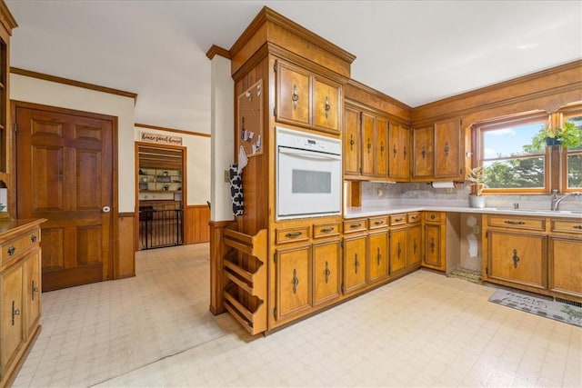 106 Emma Dr, Honea Path, SC 29654 - kitchen with oven, brown cabinetry, wainscoting, light countertops, and decorative backsplash