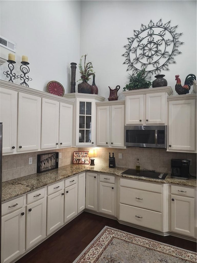 256 Chickadee Trl, Easley, SC 29642 - kitchen featuring stainless steel microwave, black electric stovetop, tasteful backsplash, and dark wood-style flooring