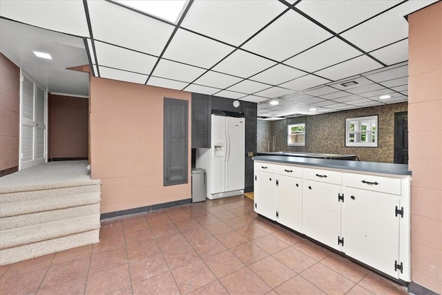 1122 Cox Rd, Anderson, SC 29621 - kitchen featuring white fridge with ice dispenser, white cabinetry, tile patterned flooring, a drop ceiling, and dark countertops