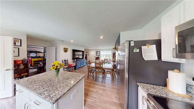112 Queens Mill Ct, Pendleton, SC 29670 - kitchen featuring white cabinets, light wood-style floors, light stone countertops, a kitchen island, and stainless steel microwave
