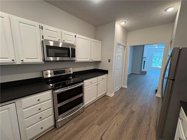 495 Tall Ship Dr Unit 340, Salem, SC 29676 - kitchen featuring stainless steel appliances, a textured ceiling, dark countertops, dark wood-type flooring, and white cabinetry