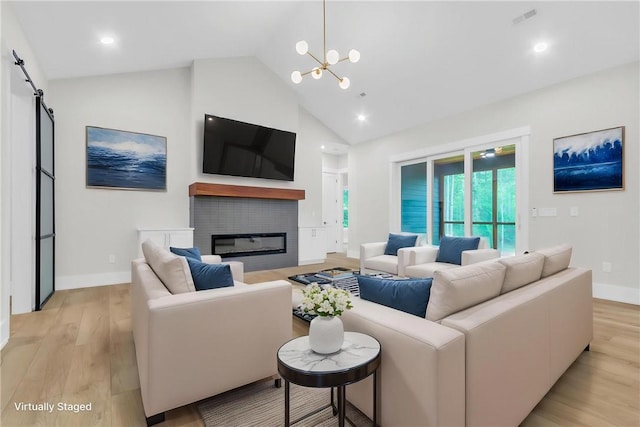 120 Thomason View Rd, Fountain Inn, SC 29644 - living room featuring high vaulted ceiling, light wood finished floors, a chandelier, a barn door, and a glass covered fireplace