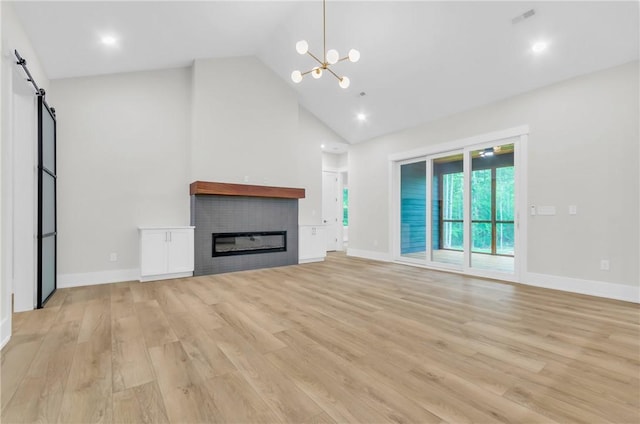 120 Thomason View Rd, Fountain Inn, SC 29644 - unfurnished living room featuring high vaulted ceiling, a barn door, light wood-style floors, a chandelier, and a glass covered fireplace