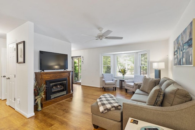 199 Mountain Rest Lake Rd, Mountain Rest, SC 29664 - living room featuring light wood-style flooring, a ceiling fan, a glass covered fireplace, and baseboards