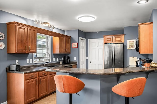 169 Campbell Bridge Rd, Seneca, SC 29678 - kitchen with freestanding refrigerator, a breakfast bar, a peninsula, a sink, and brown cabinetry