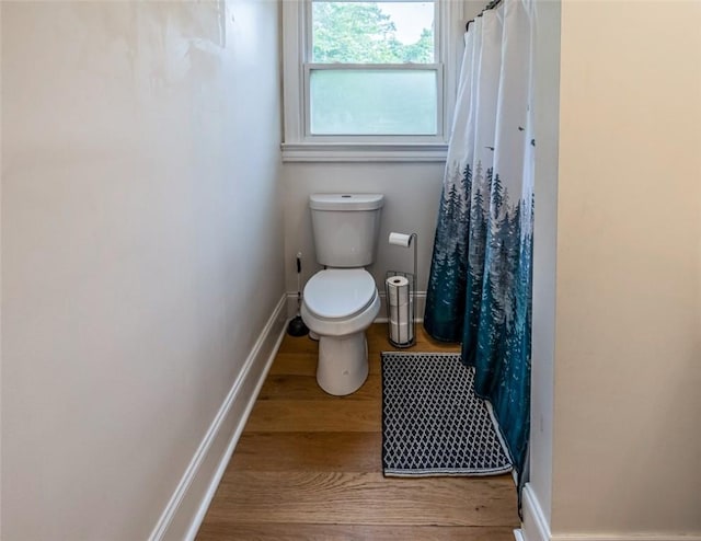 6913 White Horse Rd, Greenville, SC 29611 - bathroom with wood finished floors, toilet, baseboards, and a shower with shower curtain