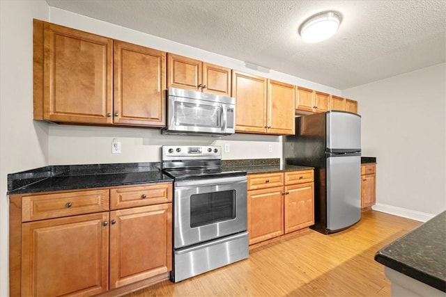 1814 Muscovy Way, Seneca, SC 29678 - kitchen featuring stainless steel appliances, light wood-style floors, a textured ceiling, dark stone counters, and brown cabinetry