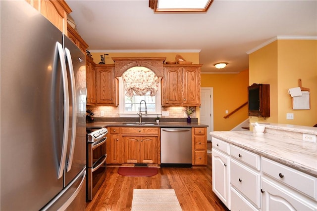 203 Tulip Tree Ct, Easley, SC 29642 - kitchen featuring stainless steel appliances, a sink, wood finished floors, decorative backsplash, and crown molding