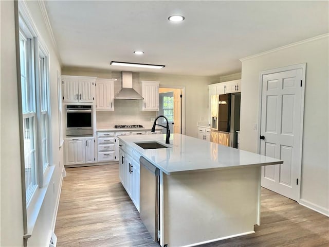 102 Buckingham Ct, Easley, SC 29640 - kitchen featuring appliances with stainless steel finishes, wall chimney exhaust hood, a sink, white cabinetry, and ornamental molding