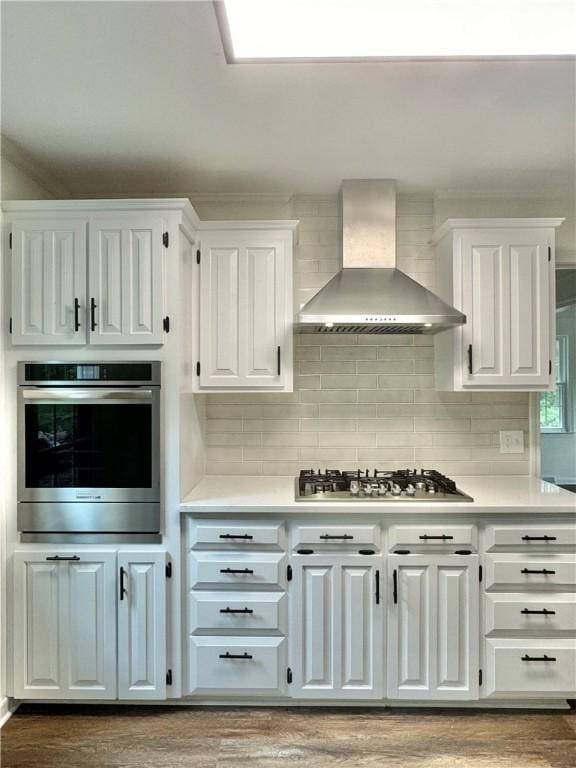 102 Buckingham Ct, Easley, SC 29640 - kitchen featuring wall chimney exhaust hood, stainless steel appliances, white cabinetry, light countertops, and wood finished floors