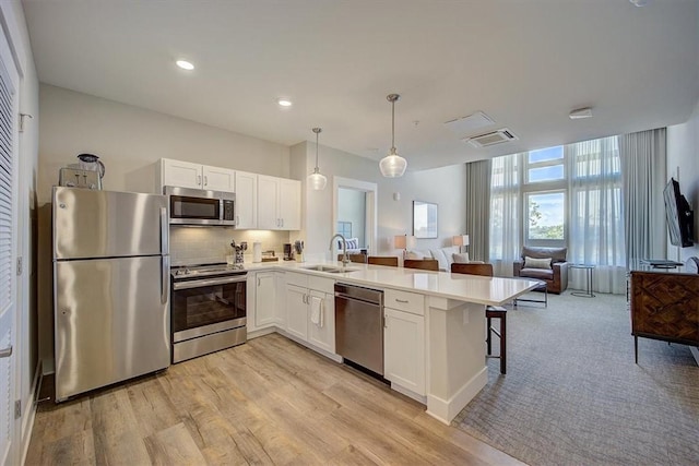 13500 Clemson Blvd Unit 2410, Seneca, SC 29678 - kitchen featuring appliances with stainless steel finishes, open floor plan, a peninsula, white cabinetry, and light wood-style floors