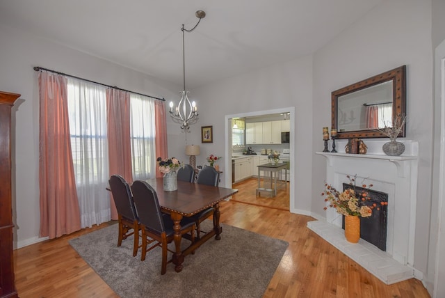 102 Langely St, Abbeville, SC 29620 - dining room with a chandelier, light wood-type flooring, and a fireplace with raised hearth