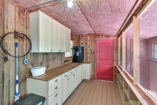 197 Jubie Ln, Seneca, SC 29672 - kitchen with lofted ceiling, wood walls, light wood-style flooring, white cabinetry, and fridge
