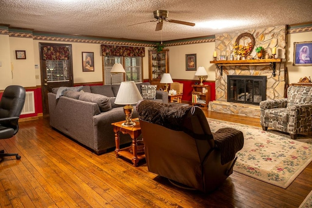 316 Brewer Rd, Walhalla, SC 29691 - living room featuring a textured ceiling, a ceiling fan, wood-type flooring, a fireplace, and a wainscoted wall