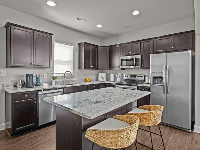 112 Wilbur St, Easley, SC 29640 - kitchen with appliances with stainless steel finishes, dark brown cabinetry, dark wood-style floors, a center island, and light stone countertops
