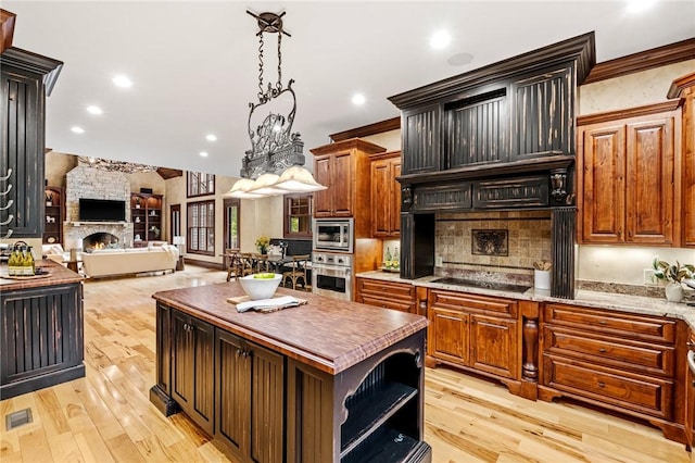 264 Featherstone Dr, Sunset, SC 29685 - kitchen featuring stainless steel appliances, open floor plan, a fireplace, decorative backsplash, and light wood-style flooring