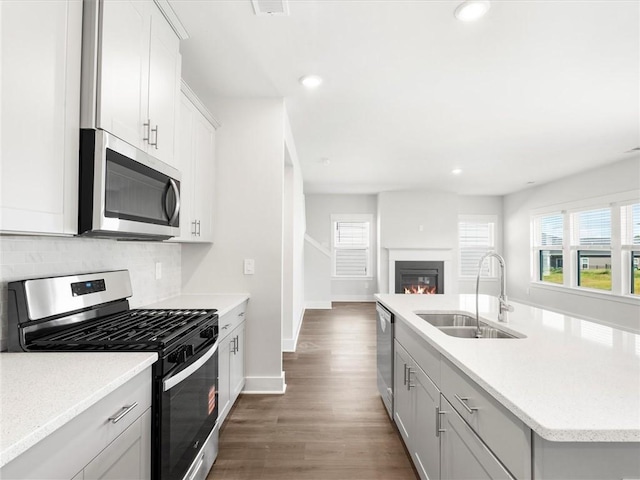 791 Burghley Cir, Greer, SC 29651 - kitchen with appliances with stainless steel finishes, backsplash, dark wood-type flooring, an island with sink, and a glass covered fireplace