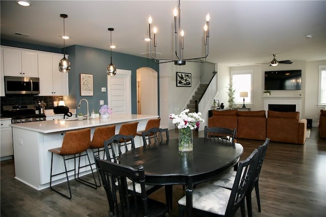 104 Laurel Oak Dr, Anderson, SC 29621 - dining area featuring stairs, dark wood-type flooring, a ceiling fan, arched walkways, and a fireplace