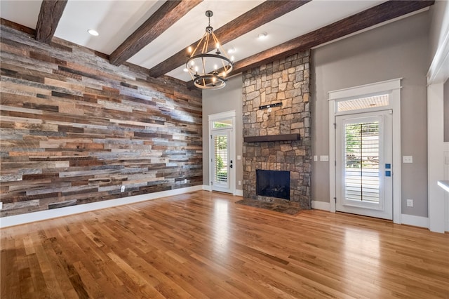 1219 Old Mill Rd, Easley, SC 29642 - unfurnished living room with wood finished floors, a chandelier, a stone fireplace, wooden walls, and beam ceiling