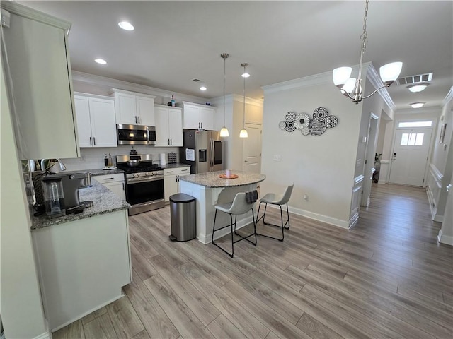 406 Willow Grove Way, Anderson, SC 29621 - kitchen featuring appliances with stainless steel finishes, crown molding, a center island, a breakfast bar, and white cabinetry