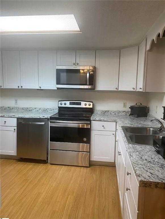 1573 John Dodd Rd, Spartanburg, SC 29303 - kitchen with stainless steel appliances, light wood finished floors, white cabinets, and light stone countertops