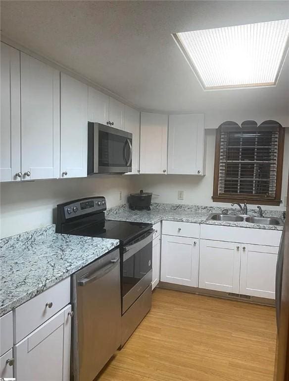 1573 John Dodd Rd, Spartanburg, SC 29303 - kitchen with appliances with stainless steel finishes, white cabinets, light stone countertops, and light wood finished floors