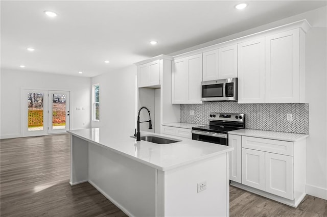 114 Hillcrest Cir, Anderson, SC 29624 - kitchen with appliances with stainless steel finishes, a kitchen island with sink, white cabinetry, wood finished floors, and tasteful backsplash