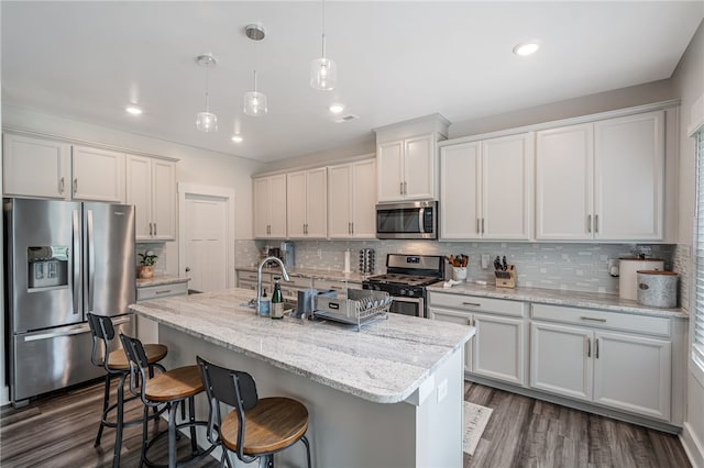 210 Obsidian Ct, Simpsonville, SC 29680 - kitchen with stainless steel appliances, tasteful backsplash, an island with sink, dark wood finished floors, and a breakfast bar area