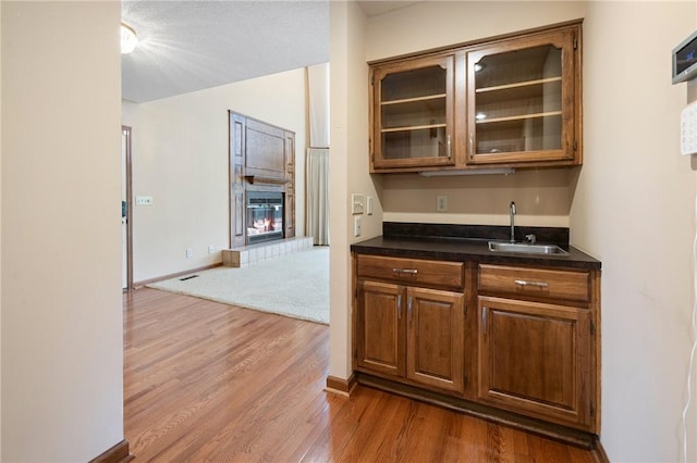 14 Windlass Ct, Salem, SC 29676 - kitchen featuring dark wood-style flooring, glass insert cabinets, a tiled fireplace, dark countertops, and brown cabinetry