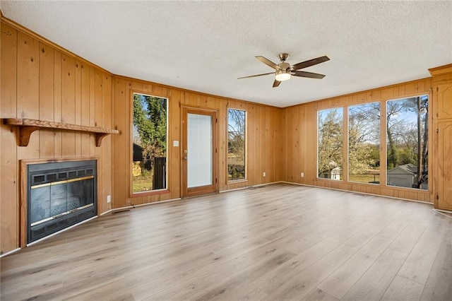 23 Gilmer Dr, Anderson, SC 29621 - unfurnished living room featuring a textured ceiling, a ceiling fan, light wood finished floors, wooden walls, and a glass covered fireplace