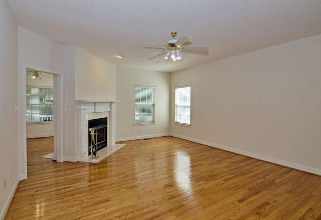 200 Smithfield Dr, Anderson, SC 29621 - unfurnished living room featuring light wood finished floors, ceiling fan, a tiled fireplace, plenty of natural light, and a textured ceiling