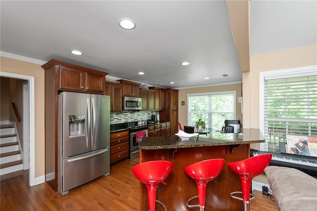 1339 Griffin Mill Rd, Easley, SC 29640 - kitchen with stainless steel appliances, ornamental molding, wood finished floors, backsplash, and a breakfast bar
