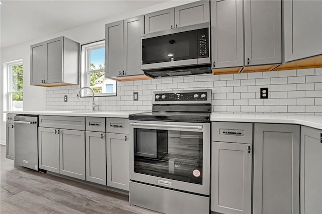 1938 Inman Dr, Anderson, SC 29625 - kitchen featuring stainless steel appliances, gray cabinetry, light wood-style flooring, light countertops, and decorative backsplash