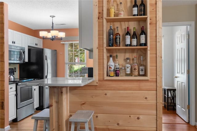 318 Weeping Willow Dr, Seneca, SC 29672 - bar area featuring appliances with stainless steel finishes, a chandelier, wood finished floors, hanging light fixtures, and a textured ceiling