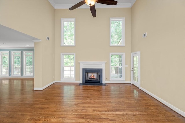 124 Bluestone Ct, Easley, SC 29642 - unfurnished living room featuring wood finished floors, a fireplace with flush hearth, crown molding, healthy amount of natural light, and a high ceiling
