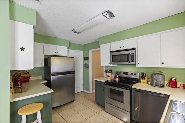 118 Nonna Ln, Seneca, SC 29678 - kitchen featuring stainless steel appliances, white cabinetry, light countertops, light tile patterned floors, and a kitchen breakfast bar