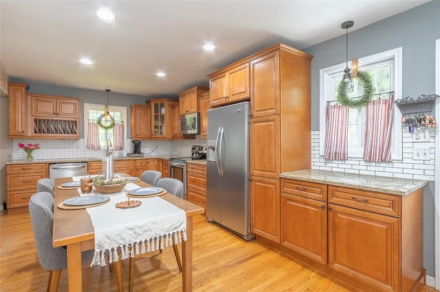 412 Singleton Rd, Anderson, SC 29625 - kitchen featuring appliances with stainless steel finishes, brown cabinets, decorative backsplash, light wood-style flooring, and hanging light fixtures