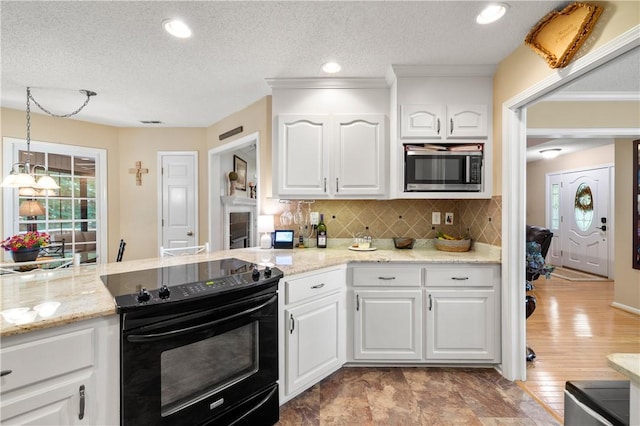 15067 Beacon Ridge Dr, Seneca, SC 29678 - kitchen with black electric range, stainless steel microwave, hanging light fixtures, white cabinetry, and a textured ceiling