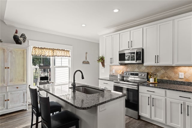 500 Serria Way, Seneca, SC 29678 - kitchen featuring stainless steel appliances, ornamental molding, dark stone counters, dark wood-style flooring, and a kitchen island with sink