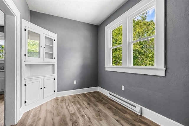 104 W Franklin St, Anderson, SC 29624 - unfurnished room with a baseboard heating unit, wood finished floors, a textured wall, and a textured ceiling