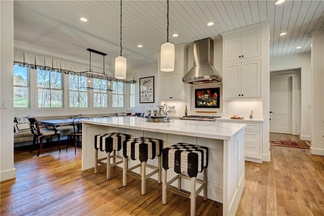 LOT10 Laurel Pond Way, Sunset, SC 29685 - kitchen with wall chimney exhaust hood, light wood-style flooring, a kitchen island, white cabinets, and recessed lighting