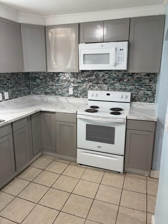 715 Delia St, Anderson, SC 29624 - kitchen with white appliances, gray cabinets, light tile patterned floors, and backsplash
