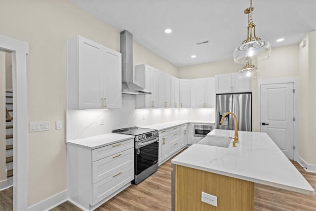 711 Concord Rd, Anderson, SC 29621 - kitchen with stainless steel appliances, wall chimney range hood, light wood-type flooring, an island with sink, and white cabinets